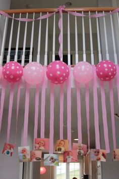 some pink and white balloons hanging from the ceiling