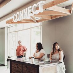 three people sitting at a counter in front of a sign that says connect on it