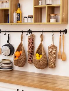 kitchen utensils hanging from hooks on the wall above a wooden counter top with plates and bowls