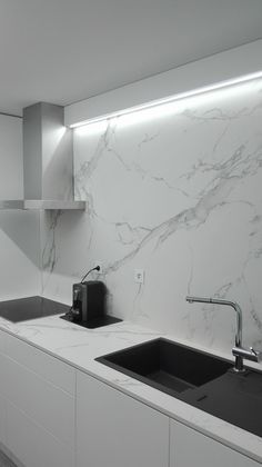 a kitchen with white marble counter tops and black sink faucets in the center