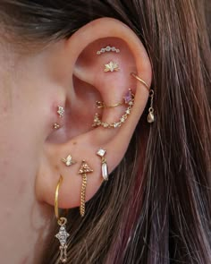 a woman wearing multiple ear piercings on her left ear and the other two are gold