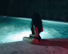 a woman sitting on the edge of a swimming pool