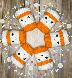 four knitted orange and white socks with faces on them, surrounded by confetti