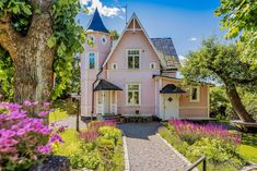 the pink house is surrounded by flowers and trees