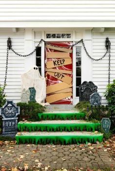 halloween decorations on the front steps of a house with a keep out sign and tombstones