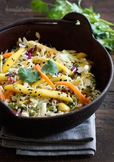 a brown bowl filled with vegetables on top of a wooden table