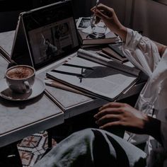 a person sitting at a table with a laptop and cup of coffee in front of them