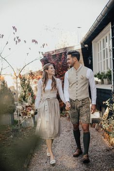 a man and woman walking down a path holding hands