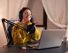 a woman sitting in front of a laptop computer wearing headphones and listening to music