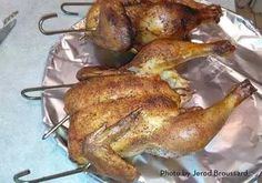 two whole chickens sitting on top of tin foil next to tongs and a knife