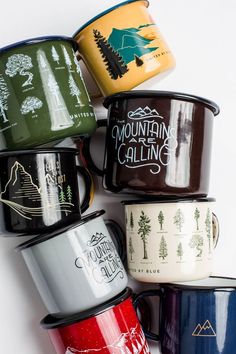 many different colored coffee mugs stacked on top of each other with the words mountain calling printed on them