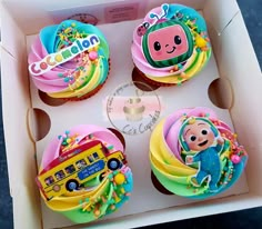 four cupcakes in a box decorated with cartoon character icing and colorful decorations