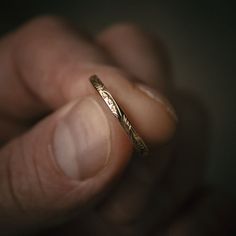 a person holding a gold ring in their left hand and the other hand is touching it