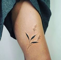 a woman's thigh with a small plant tattoo on it