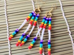 three pairs of colorful beads hanging from gold earwires on a wooden table top