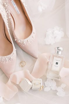 a pair of pink shoes next to a bottle of perfume