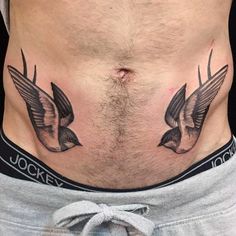 a man's stomach with two birds tattooed on the side and his lower body