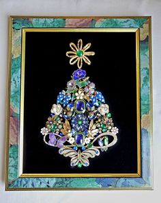 an ornately decorated christmas tree in a gold frame on a black background with blue and green flowers