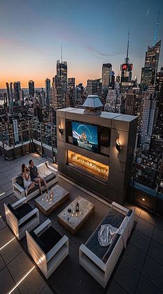 two people sitting on couches in front of a cityscape at night with the sun setting