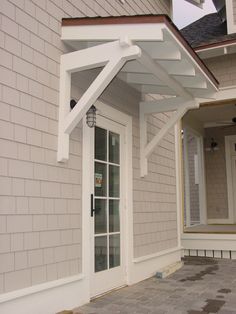 a white door and window on a gray brick house with an awning over it