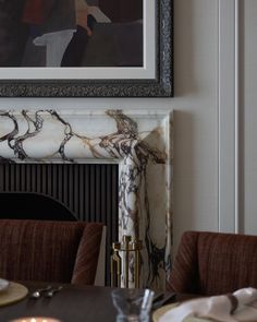 a marble fireplace mantel in a dining room with chairs and plates on the table