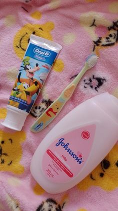 toothpaste, mouthwash and toothbrush sitting on a pink blanket with winnie the pooh characters