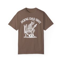 ✨💀 Introducing our "Doing Dad Shit" Skeleton T-Shirt! 💀✨ 🎉 Celebrate Father's Day with a humorous twist by gifting this custom tee featuring a skeleton on a toilet and the phrase, "Doing Dad Shit"! 🎉 💖 Crafted from 100% ring-spun cotton, this garment-dyed t-shirt offers unbeatable softness and comfort, perfect for everyday wear. 💖 😌 The soft-washed fabric adds an extra layer of coziness, making this tee an ideal choice for dads who appreciate both comfort and humor. 😌 💪 With double-needle stitching throughout, this tee is built to last, ensuring durability for all of dad's adventures. 💪 🔄 Say goodbye to bothersome side-seams – our shirt maintains its tubular shape for a sleek and flattering fit. 🔄 🎨 Show your appreciation with this fully customizable design featuring a playful Funny Father's Day T-shirt With Screen Print, Funny Screen Print T-shirt For Father's Day, Father's Day Cotton T-shirt With Graphic Print, Father's Day T-shirt With Funny Text In Relaxed Fit, Father's Day Funny Print Short Sleeve T-shirt, Father's Day T-shirt With Funny Print In Relaxed Fit, Funny Screen Print T-shirt In Relaxed Fit, Funny T-shirt For Father's Day Streetwear, Novelty Cotton T-shirt With Slogan