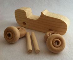 a wooden toy car with wheels and pegs on the floor next to it's contents