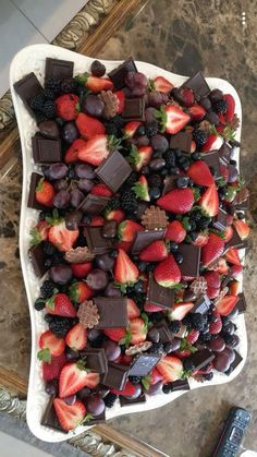 a platter filled with chocolate covered strawberries and other fruit on top of a table