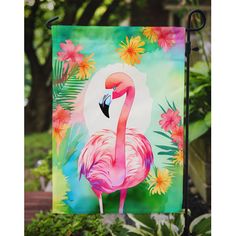 a pink flamingo standing on top of a lush green field next to trees and flowers