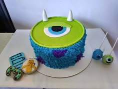 a birthday cake decorated with blue and green frosting, monster eyes and two cookies