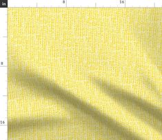 a yellow fabric with small squares and lines on it, as well as a ruler