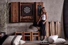 a woman leaning against a wall next to some surfboards and a table with a clock on it