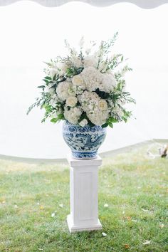 a blue and white vase filled with flowers sitting on top of a lush green field