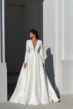 a woman in a white wedding dress is standing on the sidewalk with her back to the camera