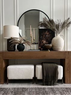 a wooden table topped with vases filled with plants and candles next to a mirror