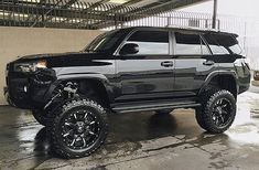 a black toyota 4runner is parked in a garage with snow on the ground and it's tires