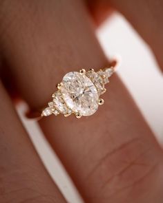 a woman's hand with a three stone ring on her left hand and the other hand holding an engagement ring