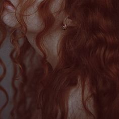 a woman with long red hair is staring into the distance