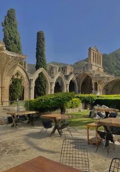 an outdoor dining area with tables and chairs in the foreground, surrounded by stone arches