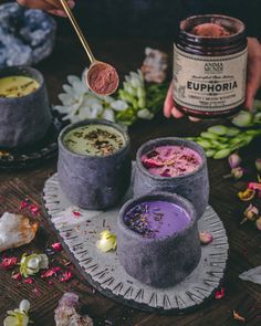 two cups filled with different colored liquids on top of a table next to flowers