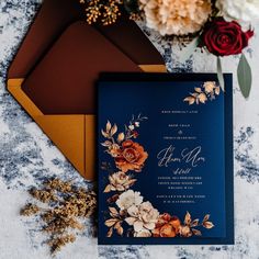 the wedding stationery is laid out on top of two envelopes and some flowers