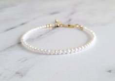 This gorgeous and dainty bracelet is made from natural pure white and high luster AAA grade freshwater seed pearls. If you're searching for a strand of high quality pearls that'll add elegance into your bracelet stack, this is the one for you! The size of the pearls are only around 3mm, extremely dainty and can be worn alone for a minimalist look too. Sterling silver, gold filled and rose gold filled finish options are available for your choosing. 14k solid yellow gold also available, but no ext White Gold Bracelet With Pearl Charm For Wedding, White Adjustable Gold Bracelet For Anniversary, White Gold Bracelet With Round Beads For Wedding, Delicate White Bracelet For Anniversary, White Gold Minimalist Wedding Bracelet, Dainty White Beaded Bracelets For Formal Occasions, White Dainty Beaded Bracelets For Formal Occasions, Delicate White Pearl Bracelet For Anniversary, White Minimalist Bracelets For Anniversary