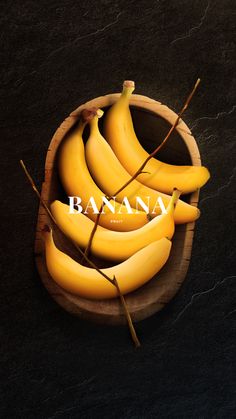 a wooden bowl filled with ripe bananas on top of a black table next to an inscription that reads banana