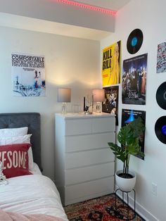 a bed room with a neatly made bed and lots of records on the wall above it