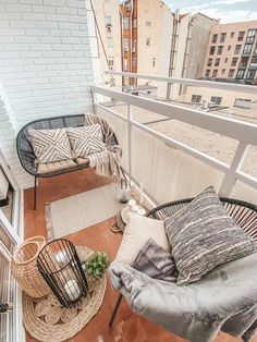 an apartment balcony with wicker furniture and pillows