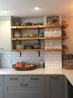 a kitchen with white tile and wooden shelves