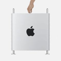 an apple computer being held by a person's hand over the top of it