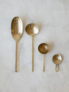 three gold spoons and one silver spoon on a marble surface