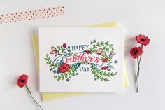 a card that says happy mother's day next to some red flowers on a white surface